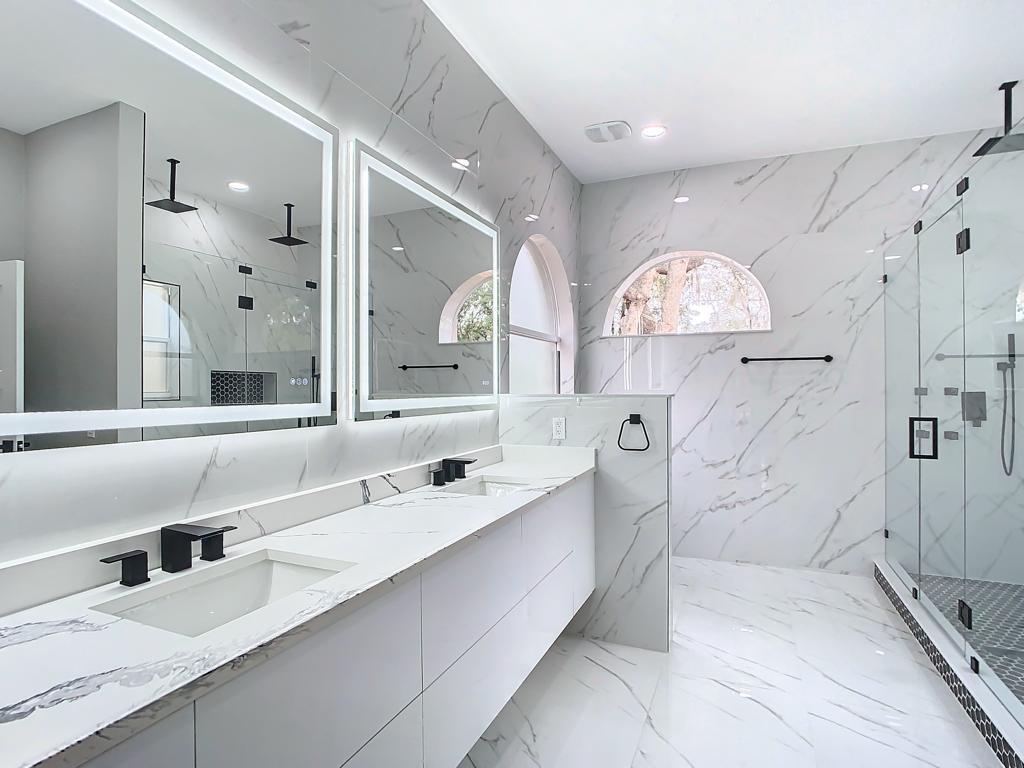 Baño renovado con tocador doble y ducha de vidrio