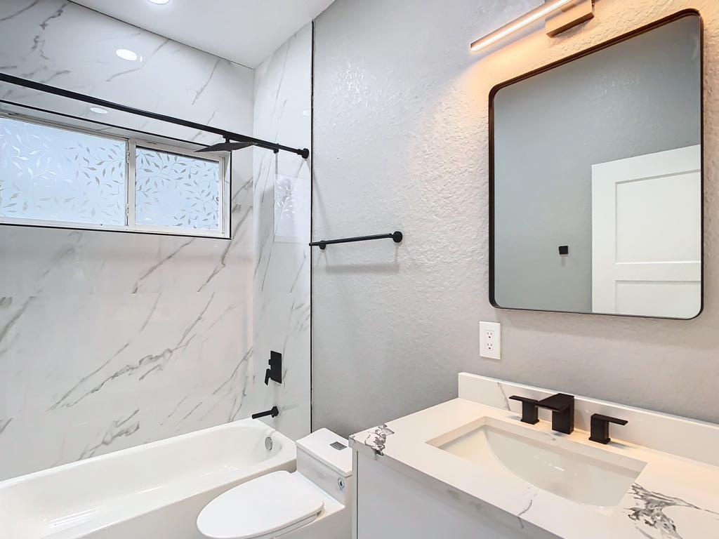 Baño renovado con bañera, tocador y ducha de vidrio